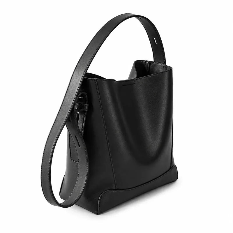 Bolsa de ombro preta em couro legítimo em vista lateral, mostrando profundidade, caimento e estrutura.