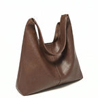 Bolsa feminina hobo marrom em couro texturizado usada pela modelo em vista lateral, com caimento e ajuste da alça