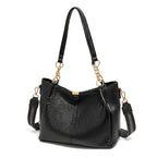 Bolsa hobo preta com corrente dourada em close no fecho e nas ferragens, com textura e brilho em destaque