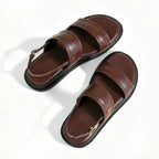 Papete marrom flatform com fivela em vista frontal, com bico, tiras e formato do par visíveis, sobre fundo claro