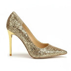 Scarpin dourado salto alto com glitter em vista lateral, com bico e perfil do salto ou solado visíveis, sobre fundo claro