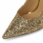Scarpin dourado salto alto com glitter em close no bico, tiras ou fivela, com textura e metal em destaque