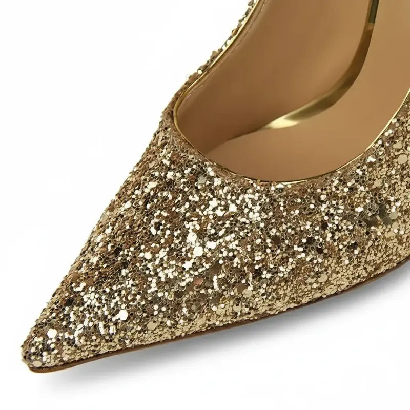 Scarpin dourado salto alto com glitter em close no bico, tiras ou fivela, com textura e metal em destaque