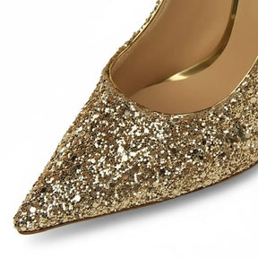 Scarpin dourado salto alto com glitter em close no bico, tiras ou fivela, com textura e metal em destaque