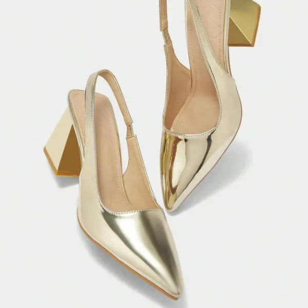 Scarpin dourado slingback salto bloco nos pés da modelo em vista frontal, mostrando ajuste e proporção, sobre fundo claro
