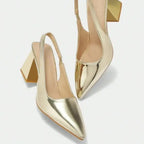 Scarpin dourado slingback salto bloco nos pés da modelo em vista frontal, mostrando ajuste e proporção, sobre fundo claro