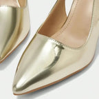 Scarpin dourado slingback salto bloco nos pés da modelo em vista lateral, destacando perfil e altura, sobre fundo claro