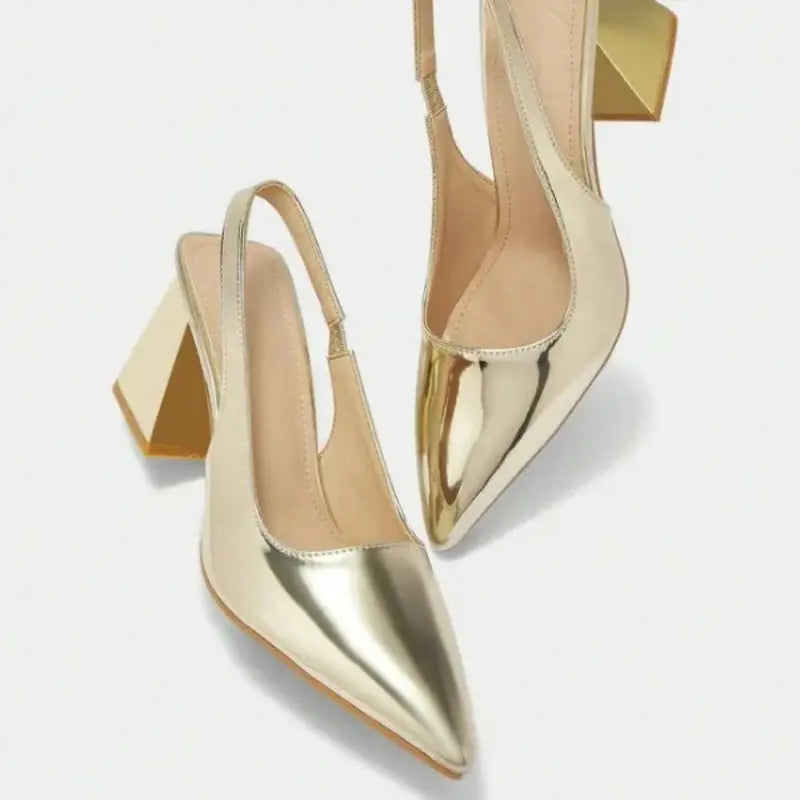 Scarpin dourado slingback salto bloco nos pés da modelo em vista frontal, mostrando ajuste e proporção, sobre fundo claro