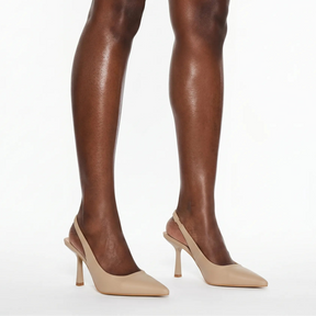 Scarpin nude salto slingback sophie nos pés da modelo em vista lateral, destacando perfil e altura, sobre fundo claro