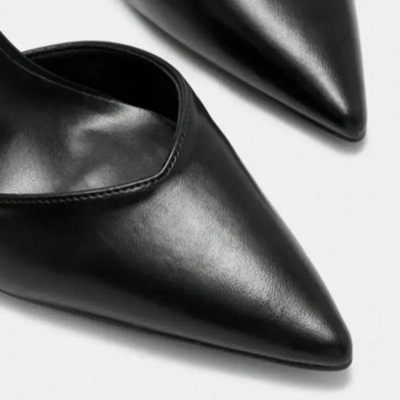 Scarpin preto com tira no tornozelo em close no bico, tiras ou fivela, com textura e metal em destaque, sobre fundo claro