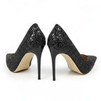 Scarpin preto salto alto com glitter em vista frontal, com bico, tiras e formato do par visíveis, sobre fundo claro