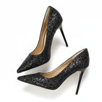 Scarpin preto salto alto com glitter em perspectiva lateral oposta, com perfil e acabamento visíveis, sobre fundo claro