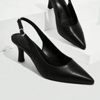 Scarpin preto slingback bico fino em vista frontal, com bico, tiras e formato do par visíveis, sobre fundo claro