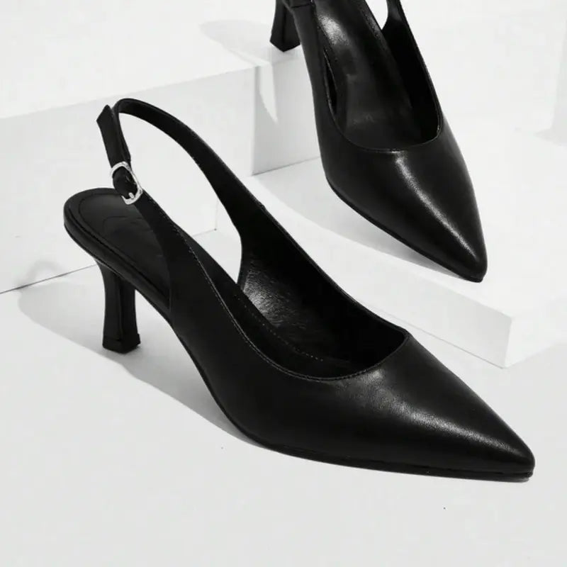 Scarpin preto slingback bico fino em vista frontal, com bico, tiras e formato do par visíveis, sobre fundo claro