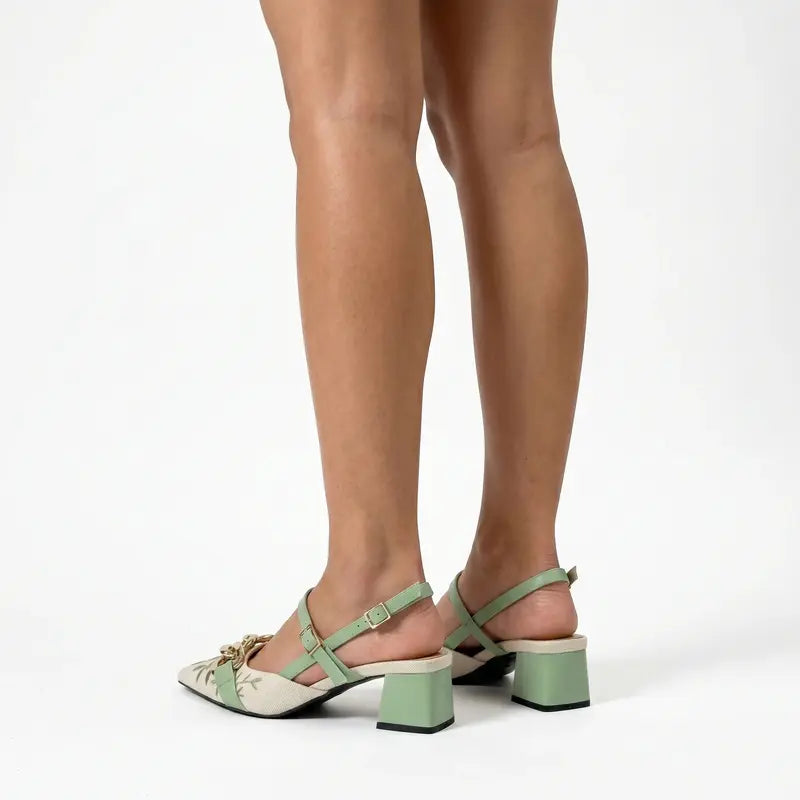 Scarpin slingback floral verde salto bloco nos pés da modelo em vista traseira, mostrando ajuste e acabamento