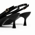 Scarpin slingback preto croco detalhe dourado em close no salto e na sola, com altura, formato e base visíveis